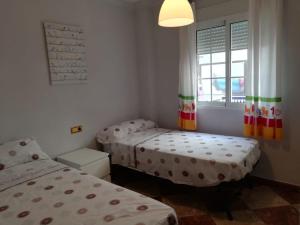 two twin beds in a room with a window at Apartamento Olivia in Nerja