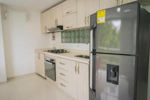 a kitchen with a stainless steel refrigerator and wooden cabinets at Exclusivo Apartaestudio en Pinares- 5 in Pereira