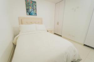 a white bedroom with a white bed and a painting at Exclusivo Apartaestudio en Pinares- 5 in Pereira