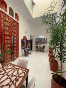 ein großes Zimmer mit Pflanzen, Tischen und Stühlen in der Unterkunft Riad Maya in Rabat