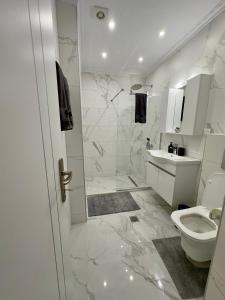 a white bathroom with a shower and a toilet at Eleni's Green balcony modern apartment by the Sea in Loutraki