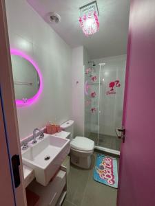 - une salle de bains avec lavabo, toilettes et lumière rose dans l'établissement Barbie House POA, à Porto Alegre