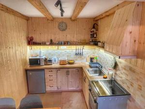 eine Küche mit Holzschränken, einer Spüle und einer Uhr in der Unterkunft Zemunica Resimić in Mokra Gora