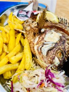 un piatto di cibo con pesce e patatine fritte di Luxury studio apartment by Hope a Bushenyi