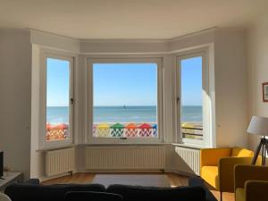 a living room with three windows and a view of the ocean at l'Éclat du Littoral Vue mer - Good Home in Dunkerque