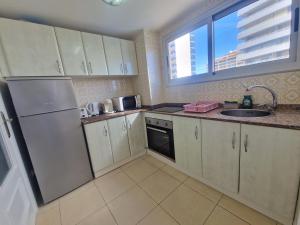 Una cocina con gabinetes blancos y un fregadero y una ventana. en Piso Calpe Playa, en Calpe