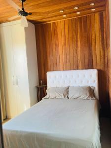 um quarto com uma cama branca e uma parede de madeira em Casa Charmosa em Taubaté