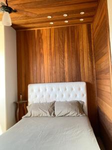 a bed in a room with a wooden wall at Casa Charmosa in Taubaté