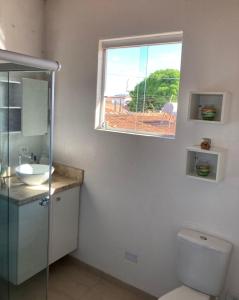 a bathroom with a toilet and a sink and a window at Casa Charmosa in Taubaté