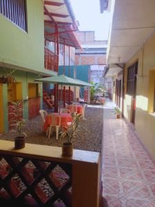 un patio con mesas, sillas y una sombrilla verde en hotel Suyay Lodge Tarapoto, en Tarapoto