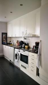 een keuken met witte kasten en een wasmachine en droger bij Arrie in in Vellinge