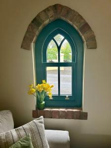 una finestra ad arco con un vaso di giunchiglie gialle davanti di The Wrens Nest ad Aghadowey