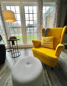 - Silla amarilla y reposapiés en la sala de estar en Mileva Retreats en Picton