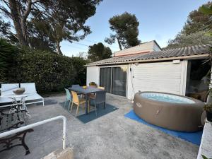 um pátio com uma mesa e uma banheira de hidromassagem em Maisonnette à 200 m de la plage em La Seyne-sur-Mer