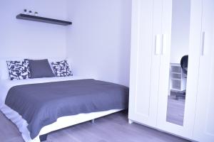 a white bedroom with a bed and a white cabinet at La Perle de Paris in Le Blanc-Mesnil