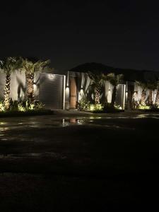 a house lit up at night with palm trees and lights at شاليهات روشانا in Taif +59 photos