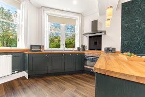 una cucina con armadi verdi scuri e una finestra di Ashbrooke Apartment Keswick a Keswick