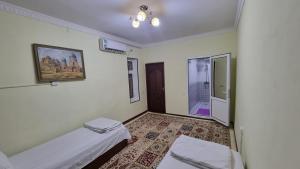um pequeno quarto com 2 camas e uma janela em Hotel Registon Zargaron em Samarkand