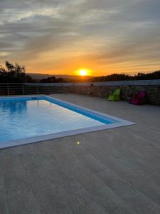 una piscina con puesta de sol en el fondo en Quinta do Esteval, en Penacova