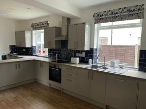 a kitchen with white cabinets and a large window at Golden Triangle Townhouse in Norwich