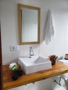 a bathroom with a white sink and a mirror at Suítes Bela Joao e Maria in Campos do Jordão