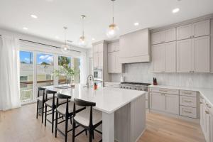 a kitchen with white cabinets and a island with bar stools at Pearl House at The Gemma by Brightwild in Clearwater Beach