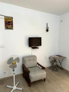 a living room with a chair and a fan at Chambre avec balcon - salle de bain extérieure privée & breakfast in Saint-Louis