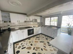 cocina grande con armarios blancos y suelo de baldosa en Casa Mirtha, en Ríohacha