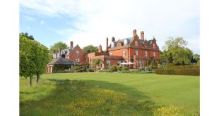 a large red brick house with a green yard at Chippenham Park Garden Rooms in Chippenham