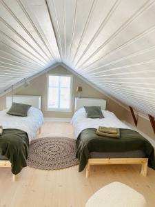two beds in a room with a ceiling at KokkolaDream - Historical Timber Home in Kokkola