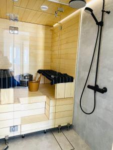 a sauna with a shower and a glass door at KokkolaDream - Historical Timber Home in Kokkola