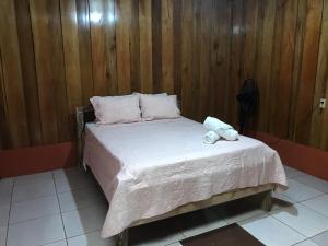 a bed in a room with a wooden wall at Jardín del descanso Arenal in San Ramón