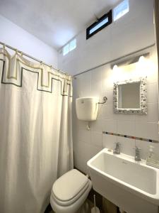 a white bathroom with a toilet and a sink at Casa espectacular directo sobre el mar in Las Flores +42 photos