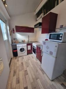 uma pequena cozinha com armários vermelhos e electrodomésticos brancos em Le Guichard - Wifi - Parking - Terrasse em Clermont-Ferrand