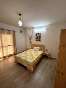 a bedroom with a bed with a yellow comforter at Chambre avec balcon - salle de bain extérieure privée & breakfast in Saint-Louis