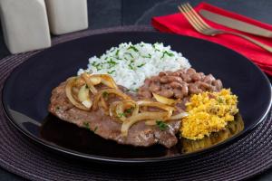 un piatto di cibo con riso, carne e fagioli di Motel Deslize Limeira 3 a Limeira