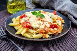 un plato de pasta con salsa y queso en una mesa en Motel Deslize Limeira 3, en Limeira