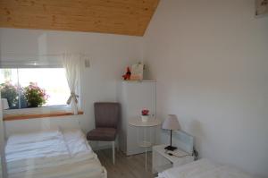 a bedroom with a bed and a chair and a window at Domki Kurka Wodna in Dębki