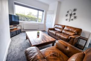 a living room with a leather couch and a table at Keith House Workstays UK 4 Bedrooms in Middlesbrough