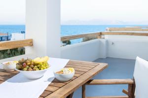 una mesa de madera con cuencos de fruta en el balcón en Alsea Seafront Apartments in Agia Pelagia Kythera, en Agia Pelagia - Citera