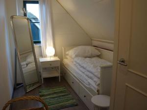 um pequeno quarto com uma cama e um espelho em Buitenplaats 79 em Callantsoog