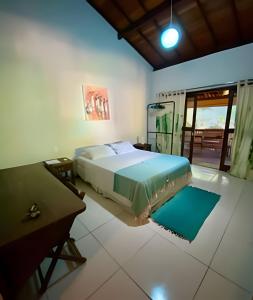 a bedroom with a large bed and a table at Flat Oxóssi em condomínio beira-mar com varandão cozinha e piscina in Marau