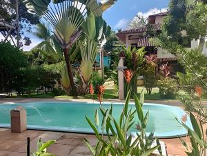 a pool in front of a house with plants at Flat Oxóssi em condomínio beira-mar com varandão cozinha e piscina in Marau