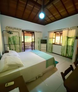 a bedroom with a large white bed and a window at Flat Oxóssi em condomínio beira-mar com varandão cozinha e piscina in Marau