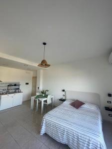 a bedroom with a bed and a table and a kitchen at "Du' I Mazzi" Stanza Etna in Giardini Naxos