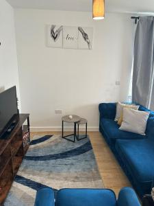 a living room with a blue couch and a table at Cosy Centrally Located Flat in Barking