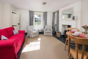 un salon avec un canapé rouge et une table dans l'établissement Garden Cottage, Teviot Bank, à Denholm 16 autres photos