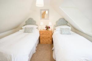 2 camas individuais num quarto no sótão com paredes brancas em Garden Cottage, Teviot Bank em Denholm