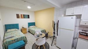 um pequeno quarto com 2 camas e um frigorífico em Hostal Turismo Quintamar 1 em Viña del Mar