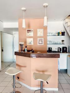 a kitchen with a pink counter and two stools at Apart Hotel no Piratas Angra dos Reis in Angra dos Reis